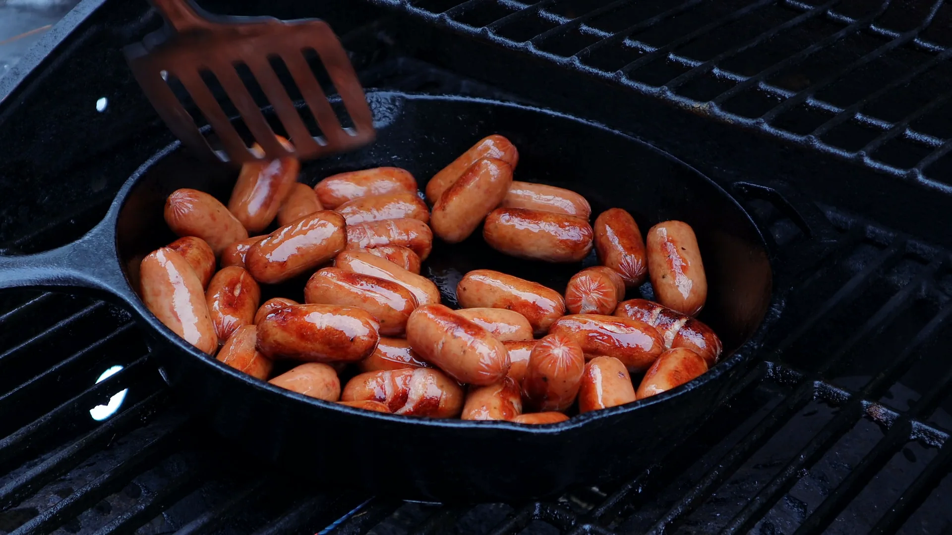 Cocktail sausages browning in a cast-iron skillet